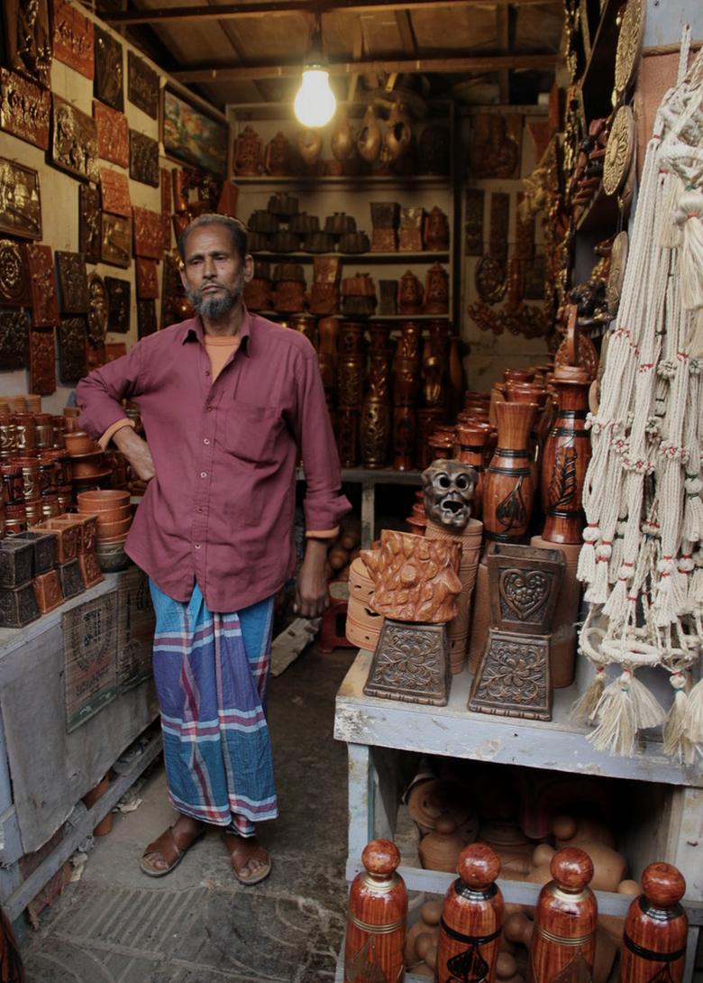 A shopkeeper standing among the brassware in his own shop in Dhaka.